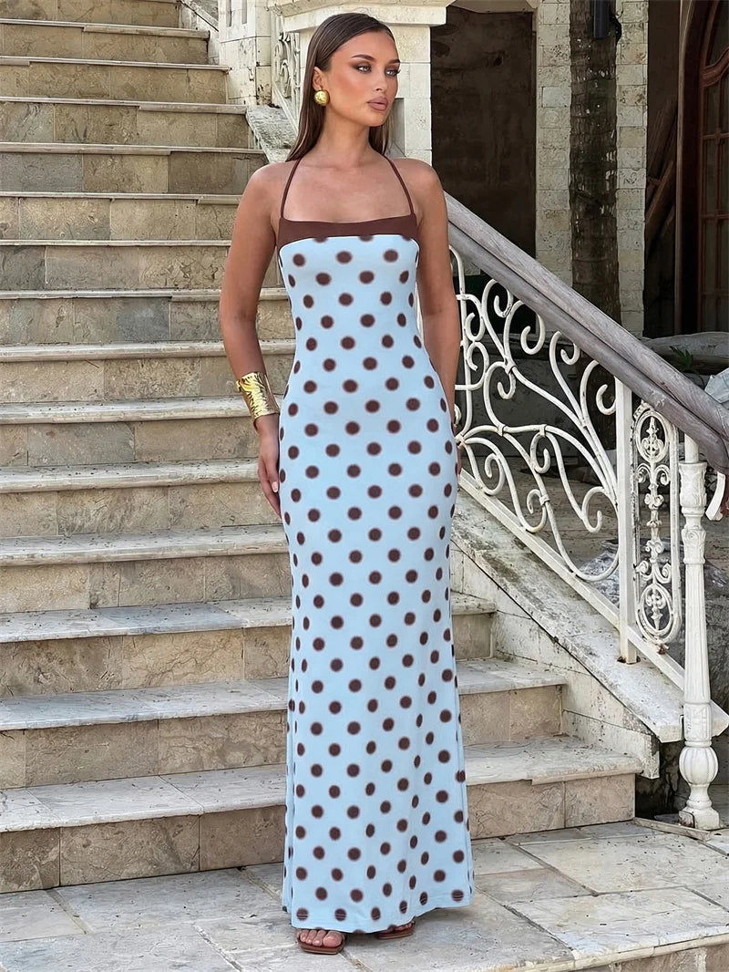 Woman in a polka dot dress standing on stone steps with decorative railing.