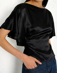 Person wearing a black satin top with ruffled sleeves on a white background