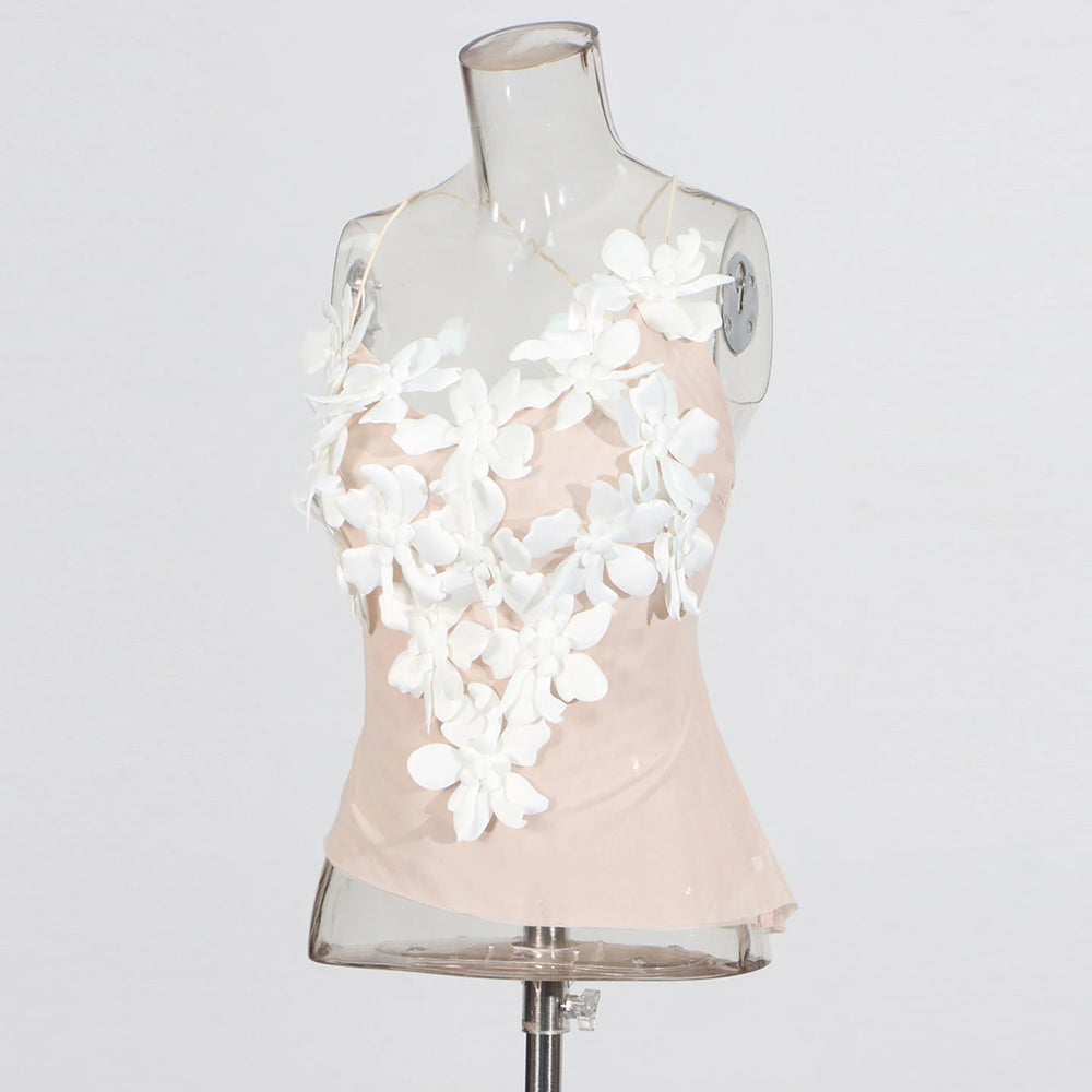 Mannequin wearing a light pink top with white floral embellishments on a plain background