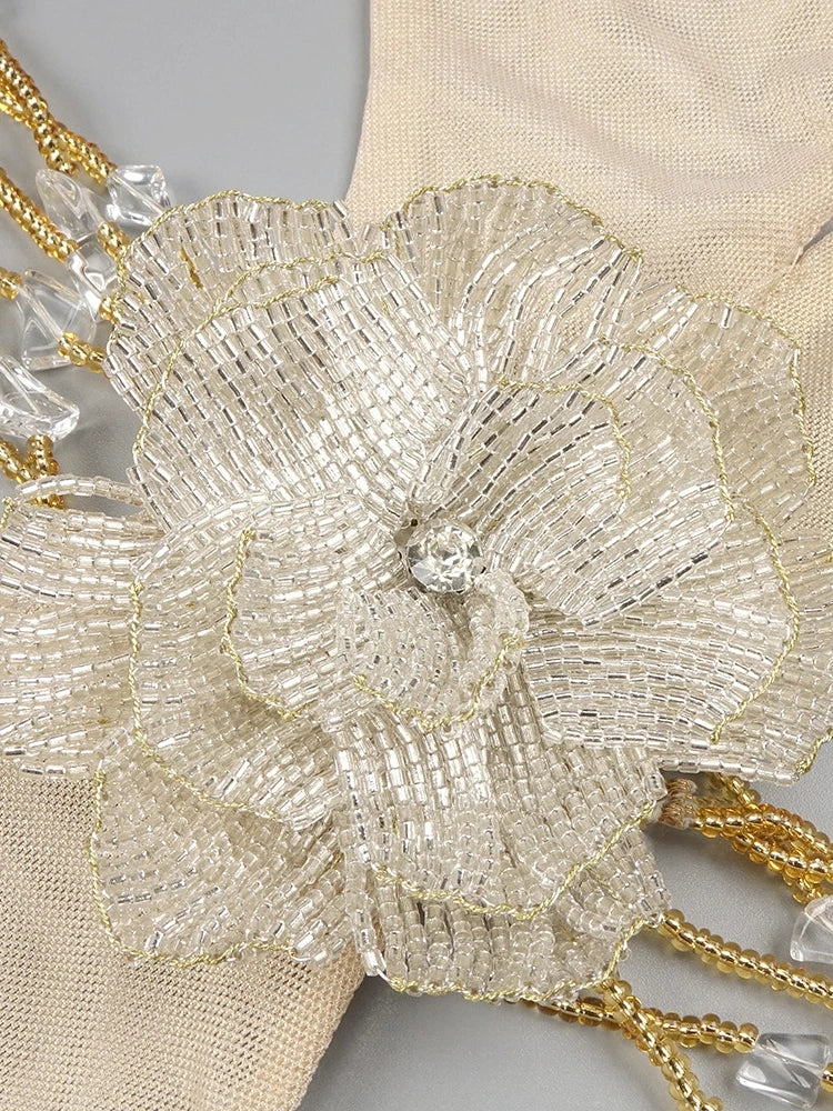 Close-up of a beaded flower accessory with gold and clear beads on a neutral background