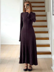 Woman taking a mirror selfie wearing a long dark dress in a home setting.