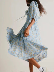 Woman wearing a light blue floral dress against a plain background