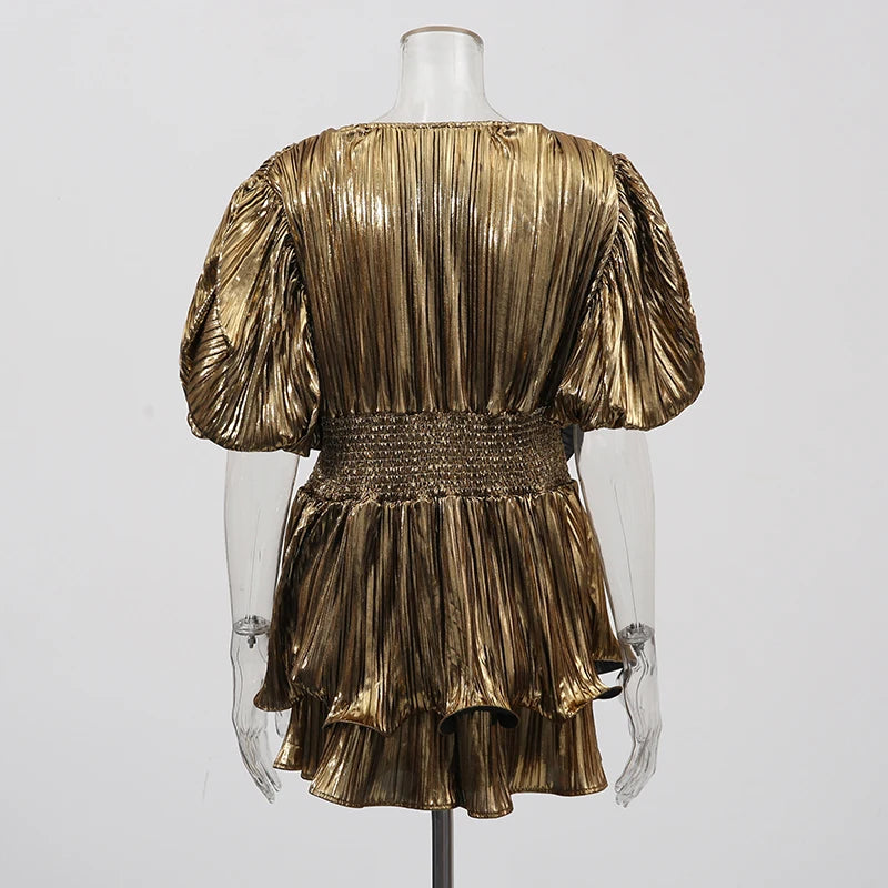 Gold pleated dress on a mannequin against a white background