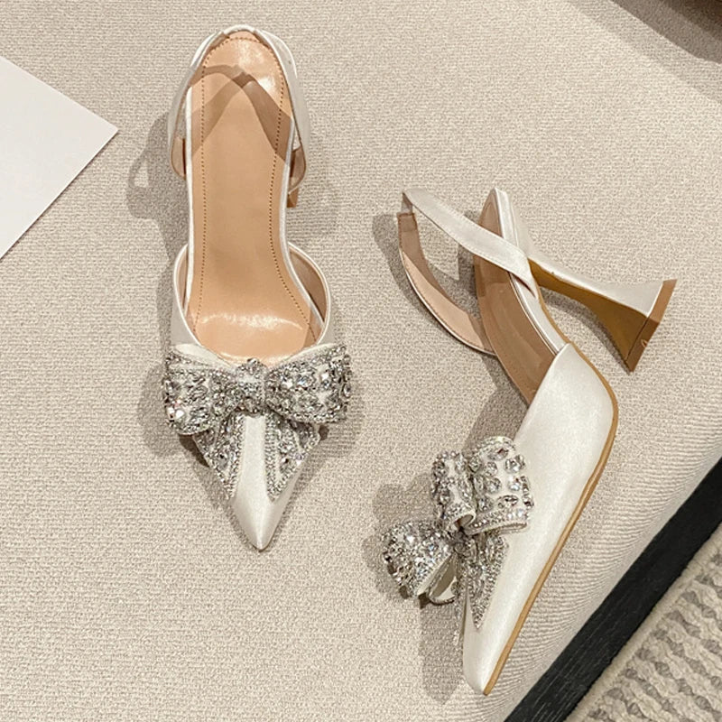 Pair of elegant high-heeled shoes with decorative bows on a textured surface