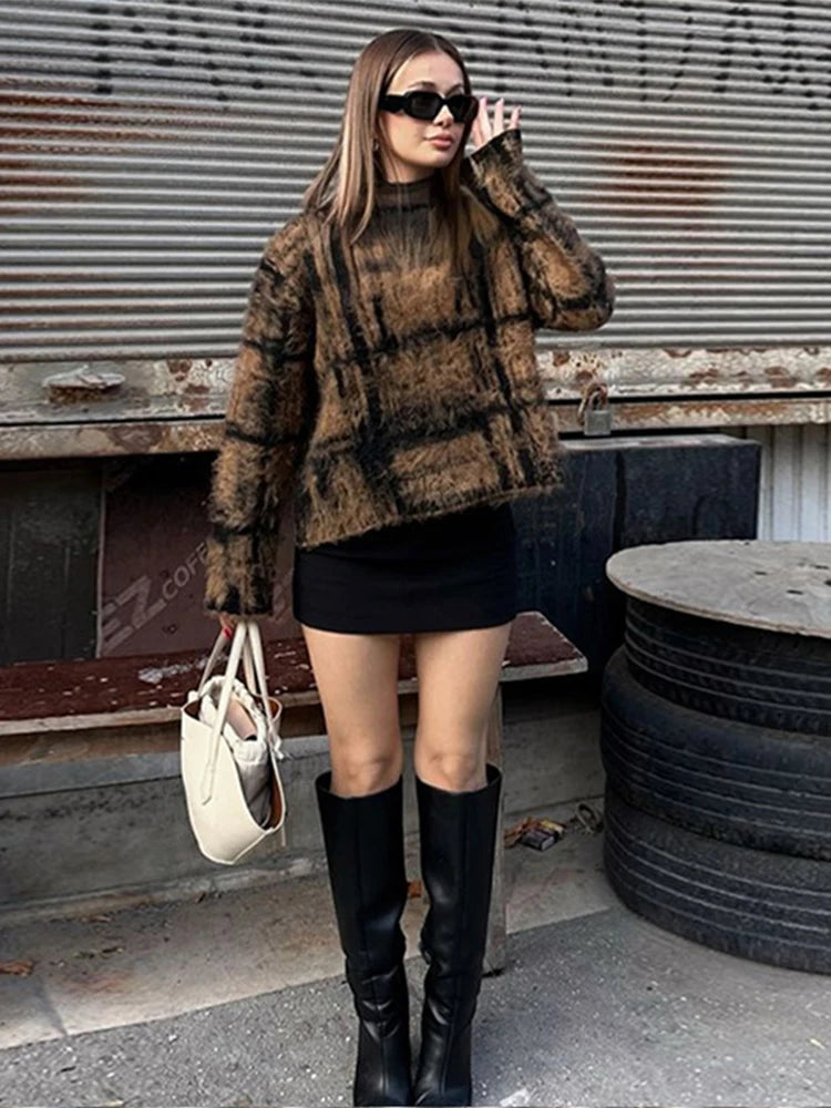 Woman wearing a plaid sweater, black skirt, and knee-high boots in an urban setting.
