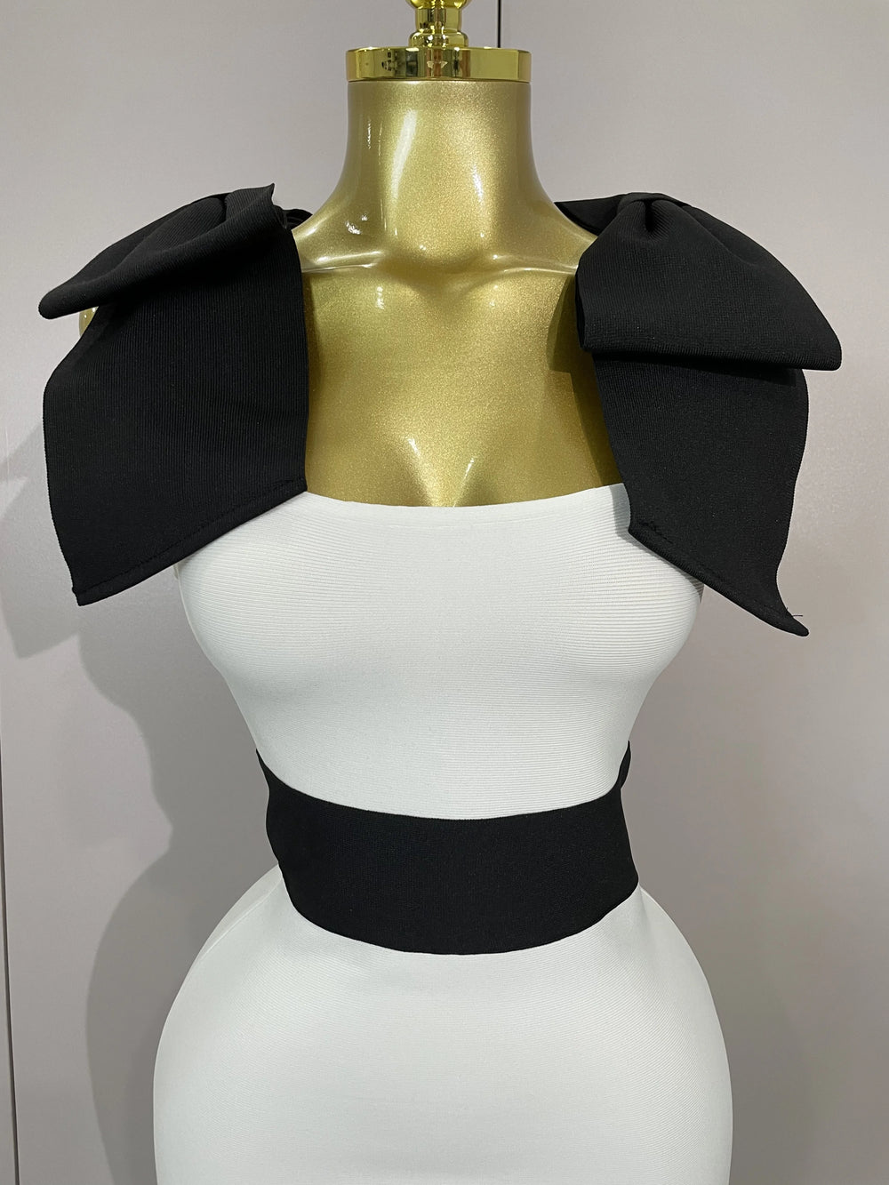 Mannequin wearing a black and white outfit with a gold top on a plain background
