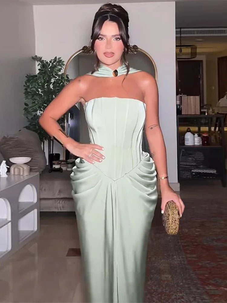 Woman in a light green strapless dress holding a clutch in an indoor setting.