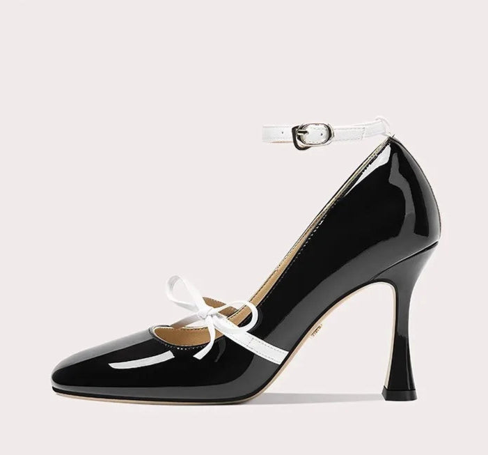 Black high-heeled shoe with white bow on a light gray background