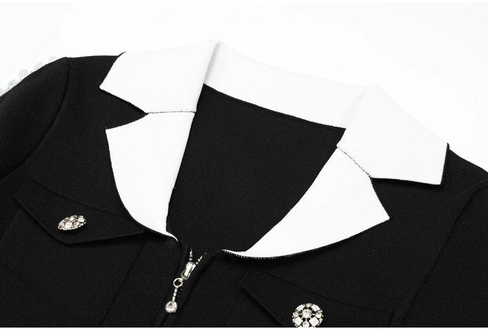 Close-up of the white collar and zipper detail on a black knit jacket.