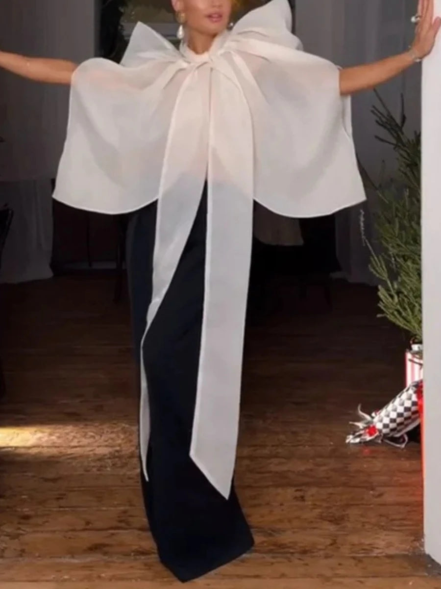 Sheer organza turtleneck top with a large bow and voluminous sleeves, paired with black trousers.