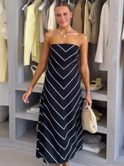 Woman wearing a strapless navy dress with white stripes in a closet.