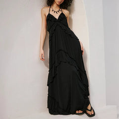 Black ruffled halter maxi dress leaning against a white wall.