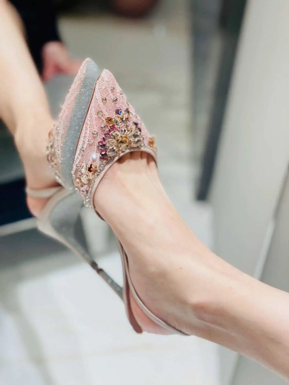 Shiny high-heeled shoes with embellishments on a blurred background