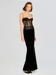 Woman wearing a black evening gown with lace detailing on a light gray background