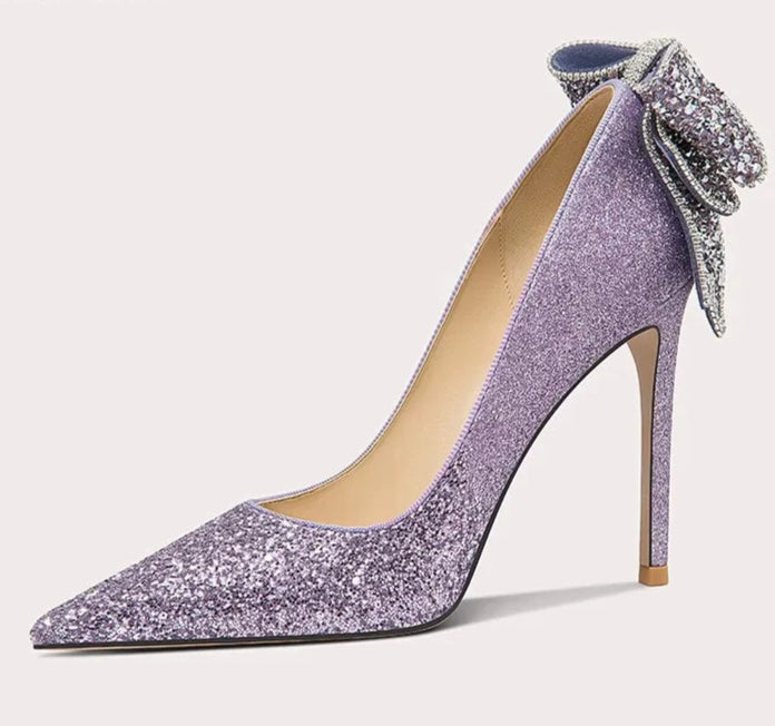 Purple high-heeled shoe with a decorative bow on a white background