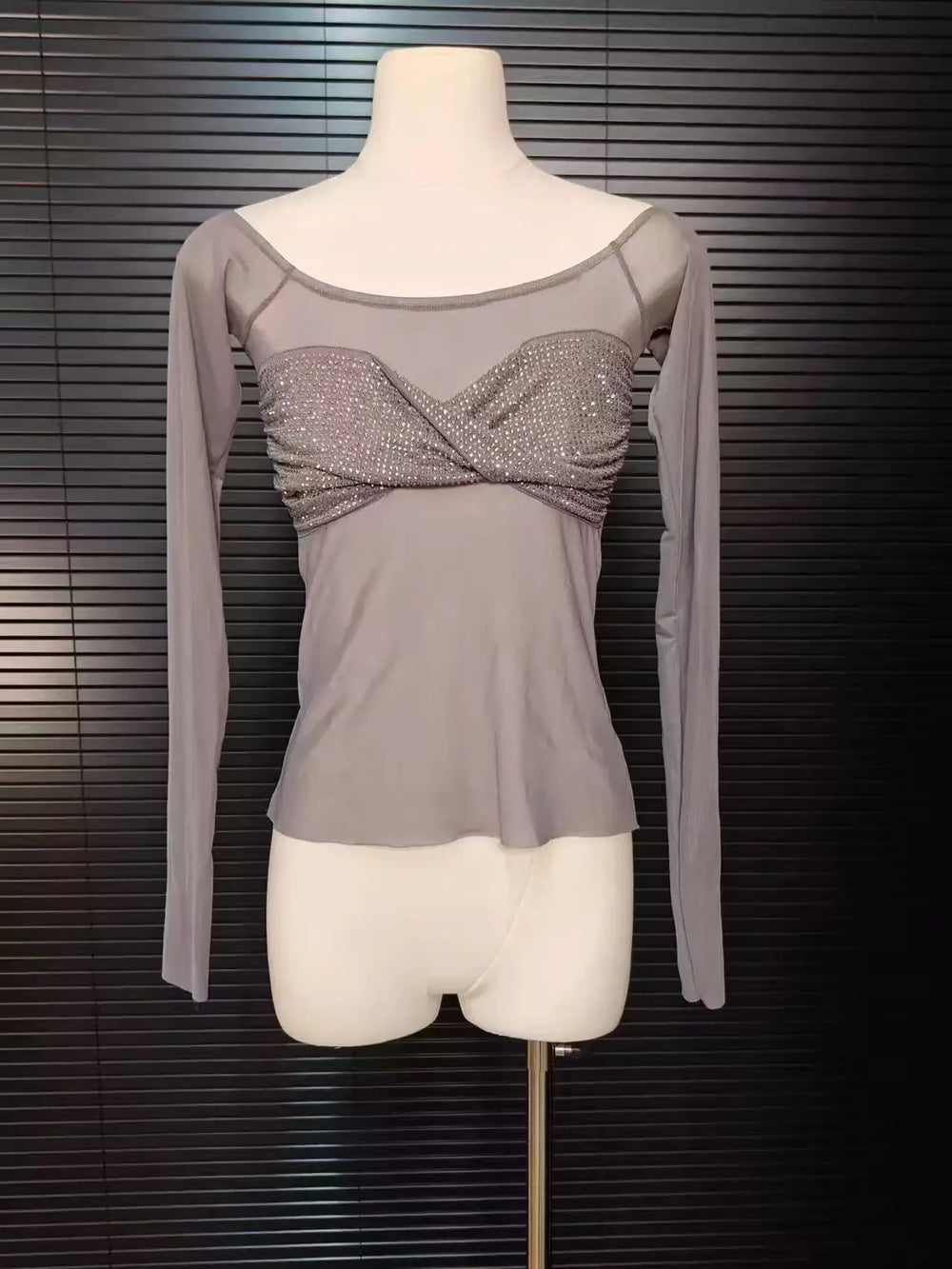 Gray long-sleeve top with a decorative front on a mannequin against a dark background