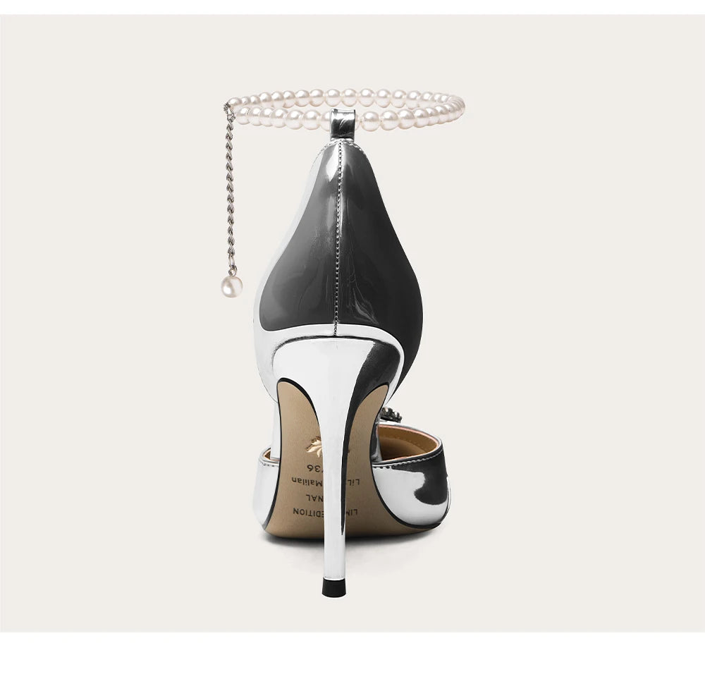 Black and white high-heeled shoe with pearl anklet on a light gray background