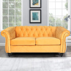 Yellow tufted sofa in a room with large windows and framed pictures on the wall.