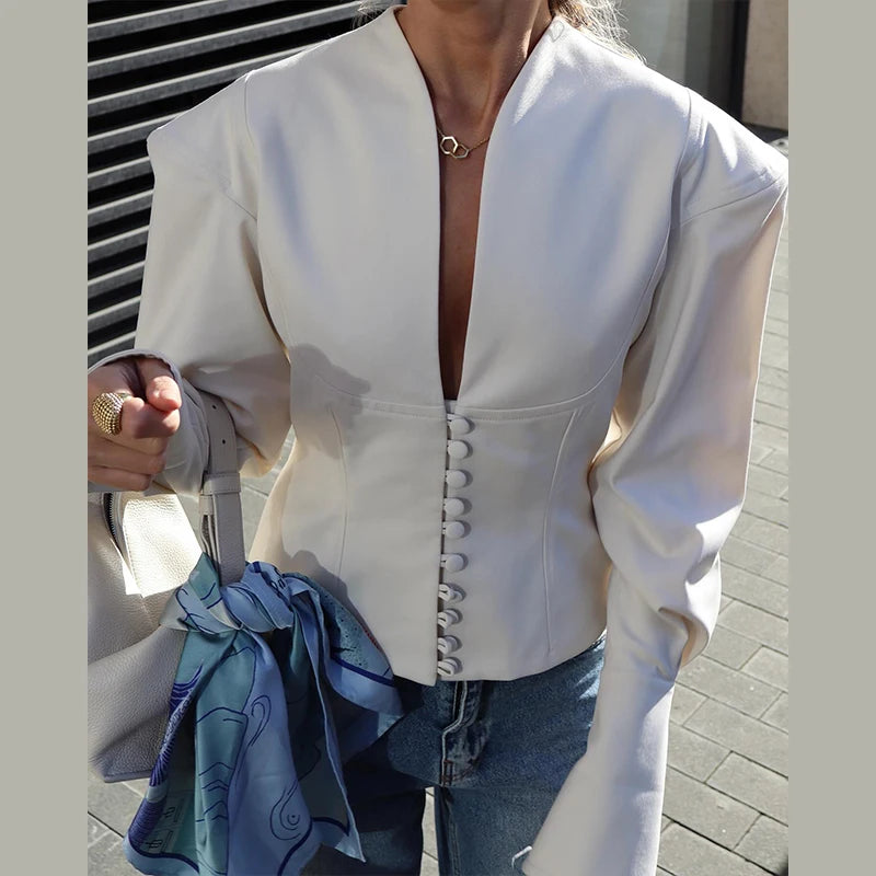Person wearing a white blouse with a deep neckline and blue jeans, holding a blue scarf.