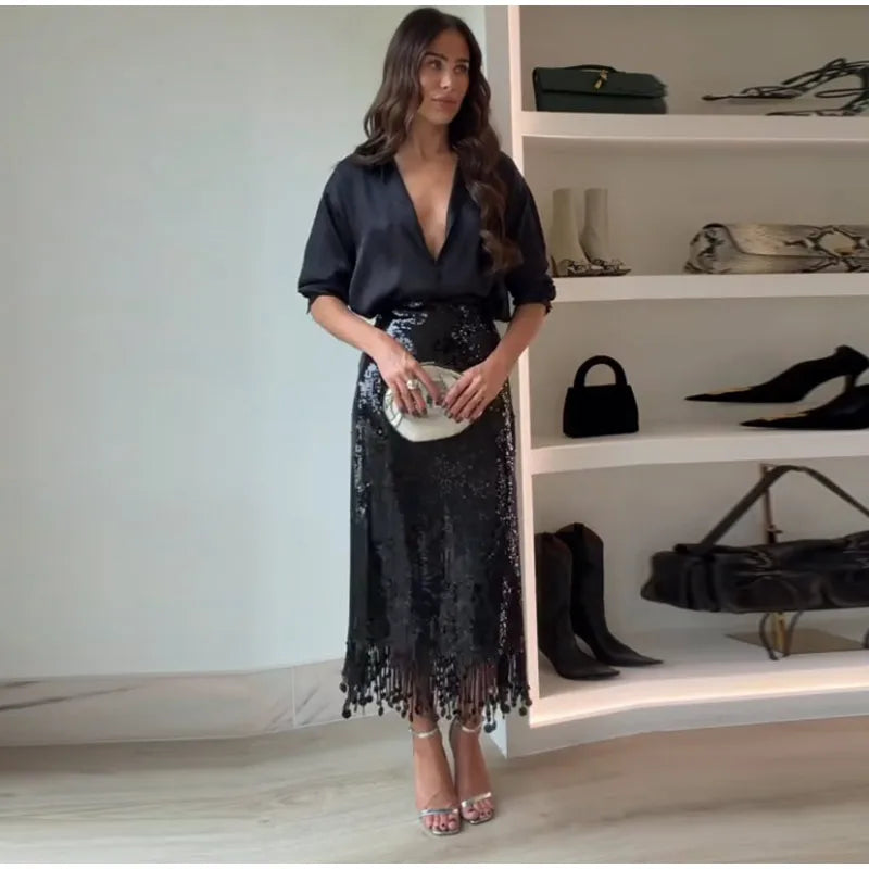 Woman in a black outfit standing in front of a shoe rack with various shoes displayed.