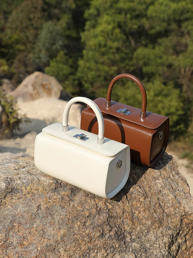 White and brown leather top handle bags on rocks