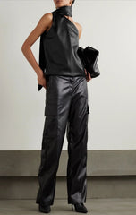 Person wearing a black leather outfit with wide-leg pants and a halter top against a plain background.