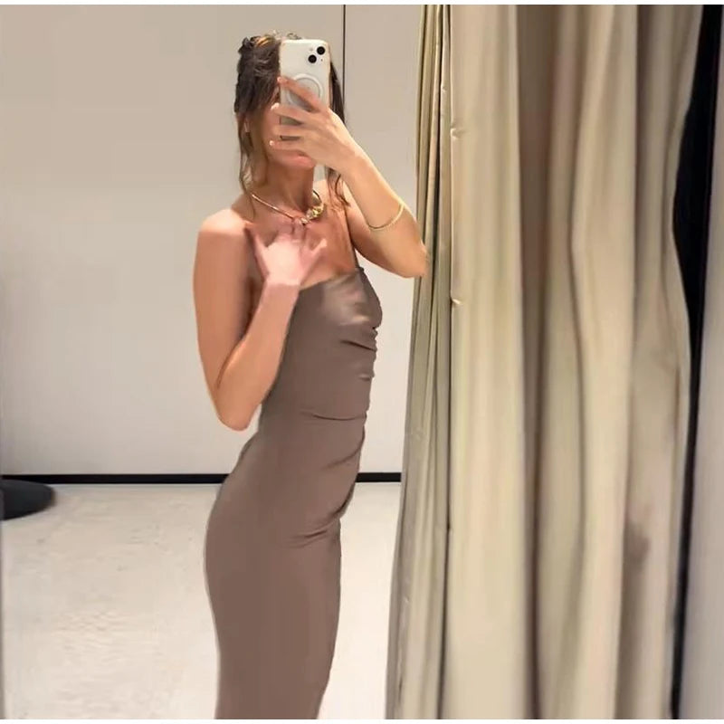 Woman taking a mirror selfie wearing a brown dress in a room with a curtain.