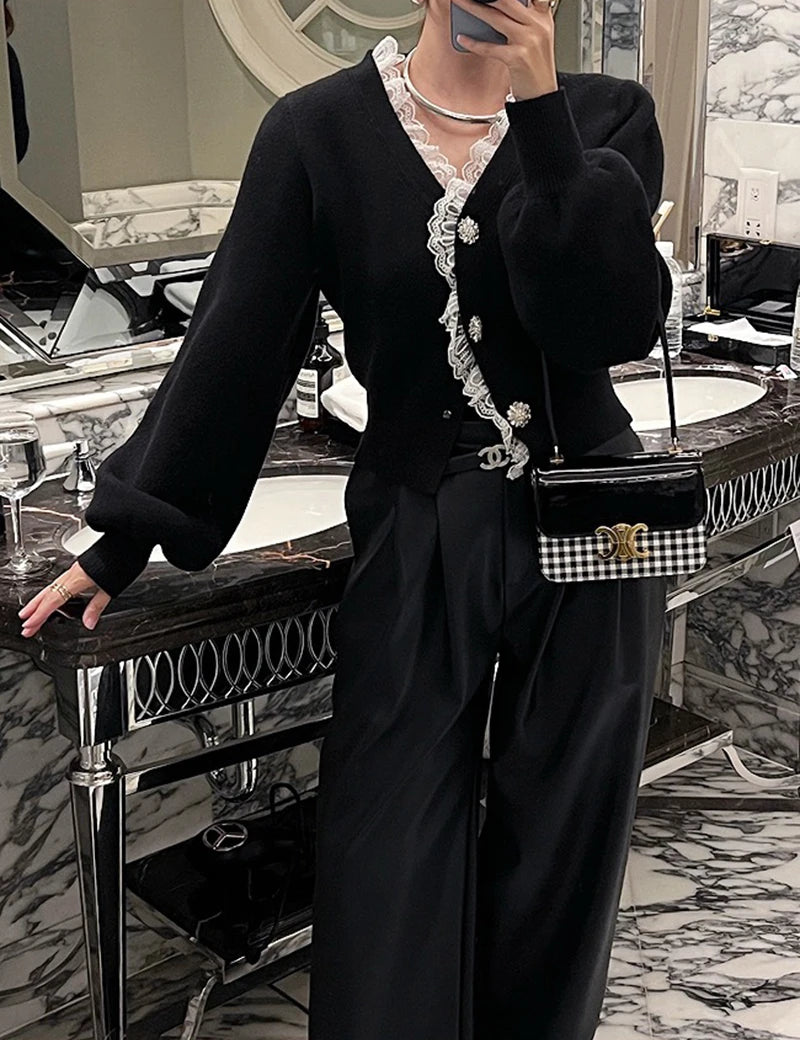 Person wearing a black outfit with lace details in an elegant interior setting.