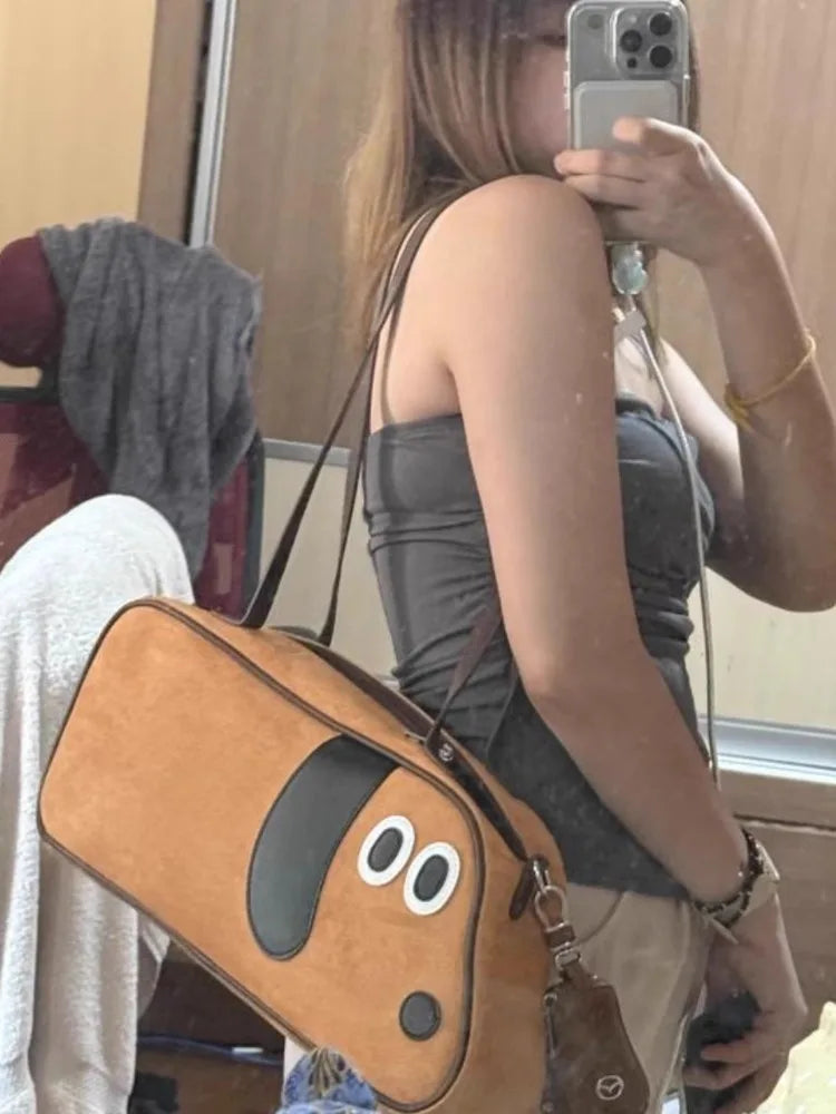 Person holding a brown dog-shaped bag in front of a mirror.