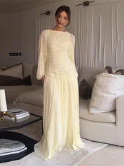Woman in a light yellow dress standing in a modern living room.