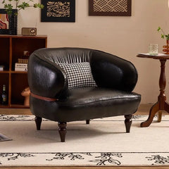 Black leather armchair with a patterned cushion in a living room setting.