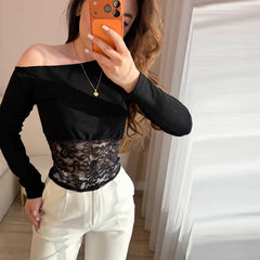 Person wearing a black off-shoulder top with lace detail and white pants, taking a mirror selfie.