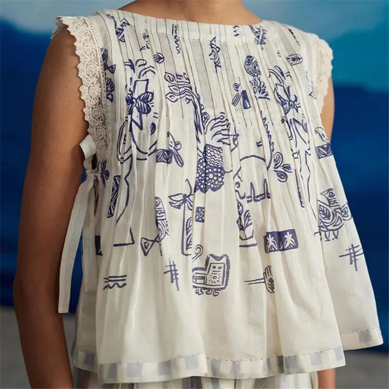 White sleeveless top with blue patterns on a blurred background