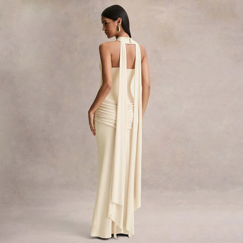 Woman wearing a long, elegant dress with a draped design against a neutral background