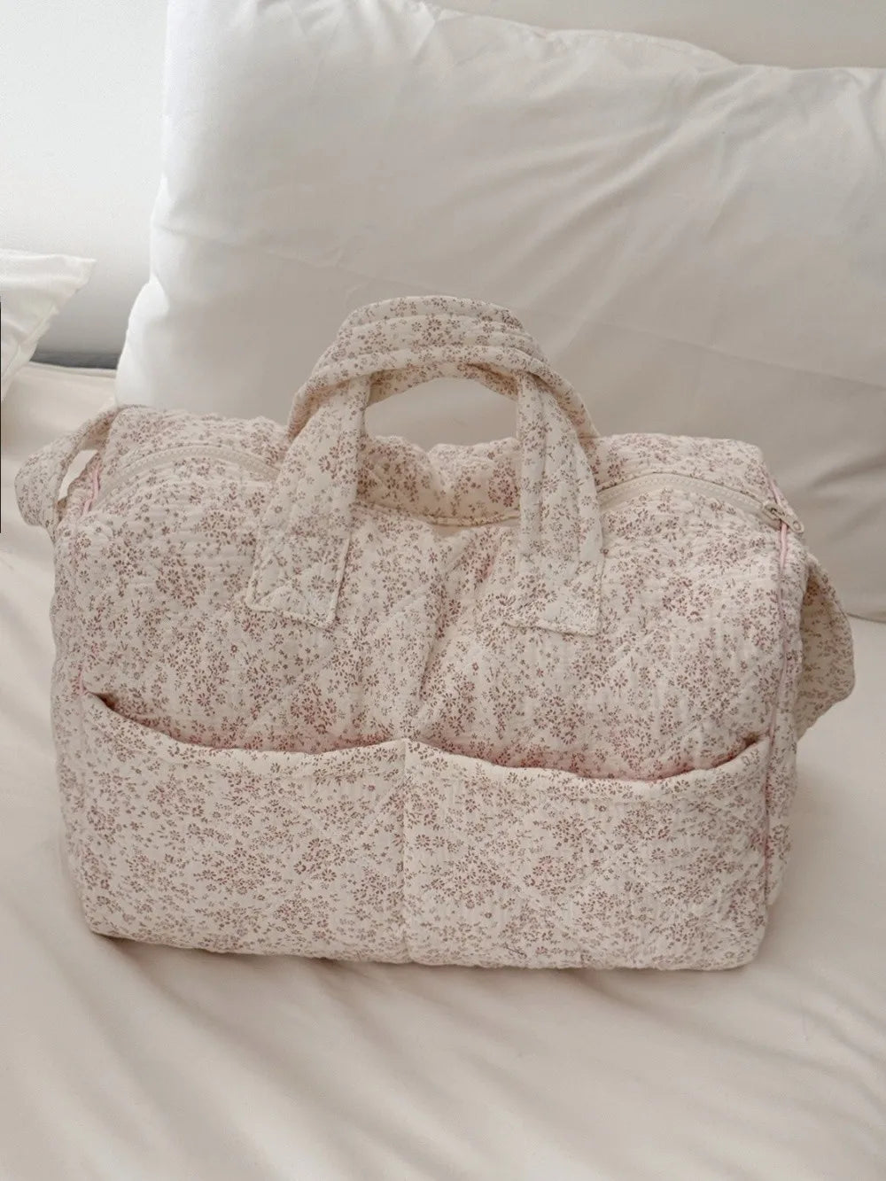 Quilted floral print duffle top, closed, resting on a bed
