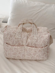 Quilted floral print duffle top, closed, resting on a bed