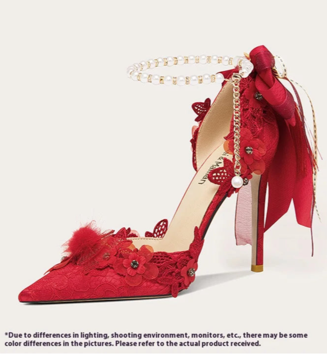 Red high-heeled shoe with floral details and a bow on a white background