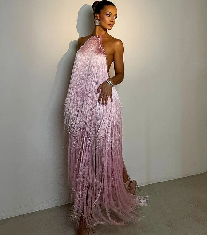 Woman wearing a pink fringe evening gown against a plain background