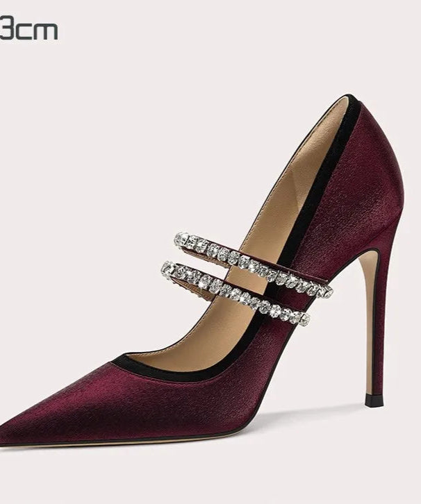 Maroon high-heeled shoe with silver straps on a light gray background