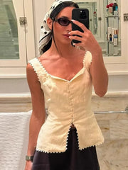A woman is taking a mirror selfie wearing a top with lace details.