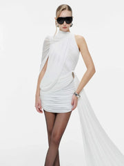 Woman wearing a white dress with flowing fabric on a plain background