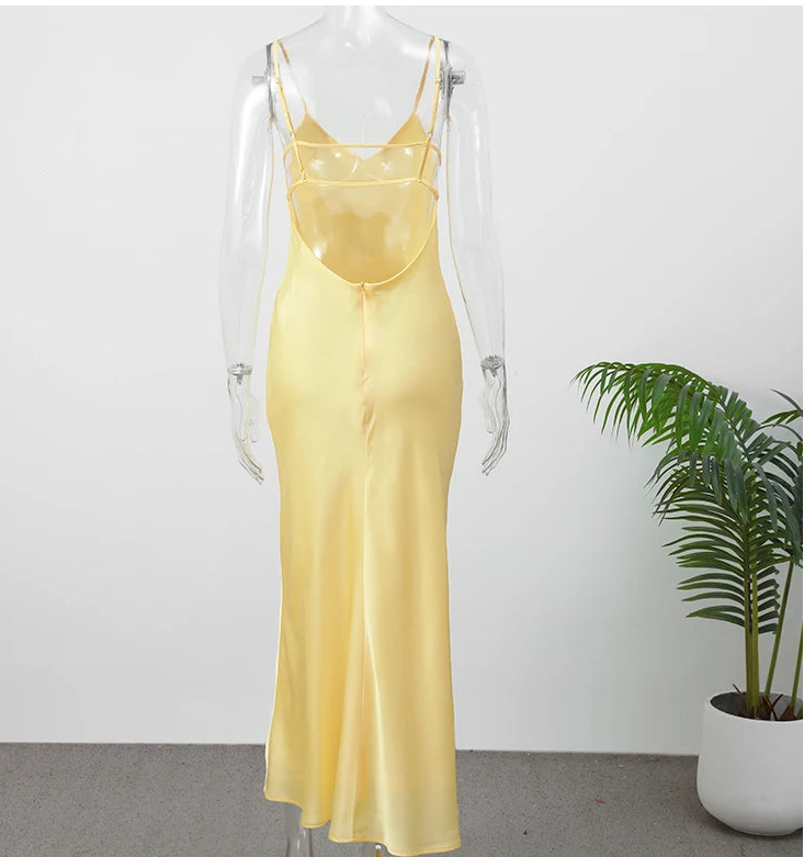 Yellow dress on a mannequin with a white background and a plant in the corner