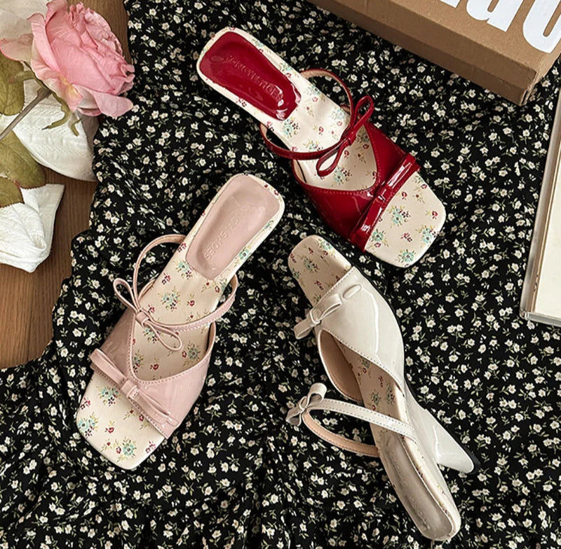 Red and white floral-patterned shoes on a black textured surface with a 'Bulu' box.