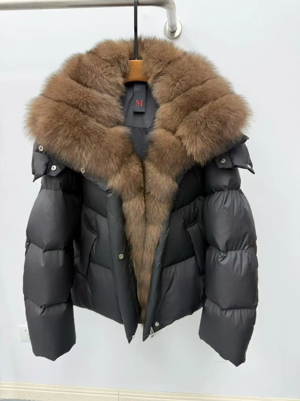Black puffer jacket with brown fur hood on a white background