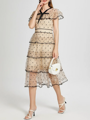 Woman wearing a floral dress with a white handbag on a plain background
