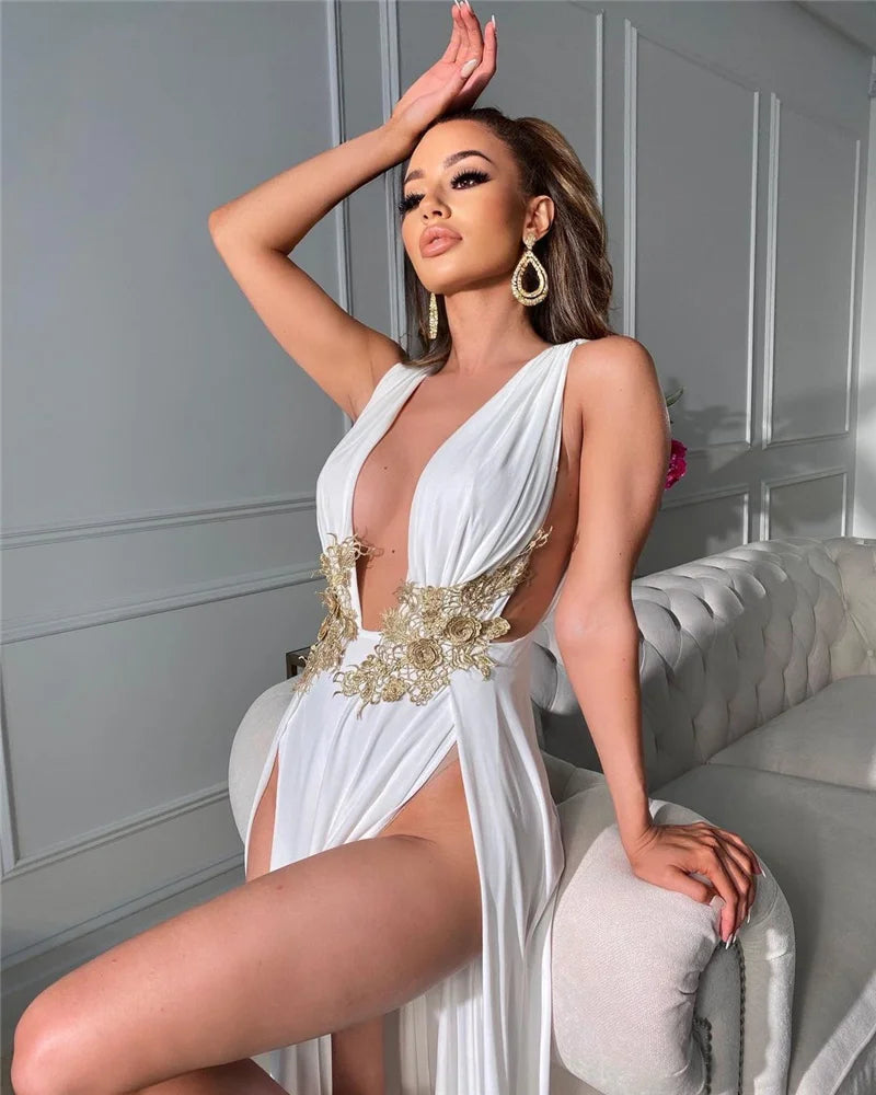 Woman in a white and gold dress posing in a stylish interior setting.