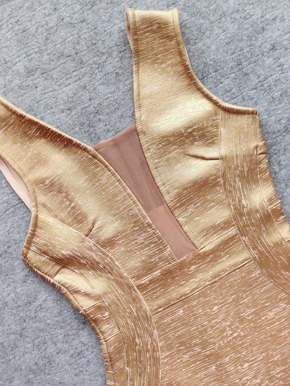 Gold swimsuit top on a gray background