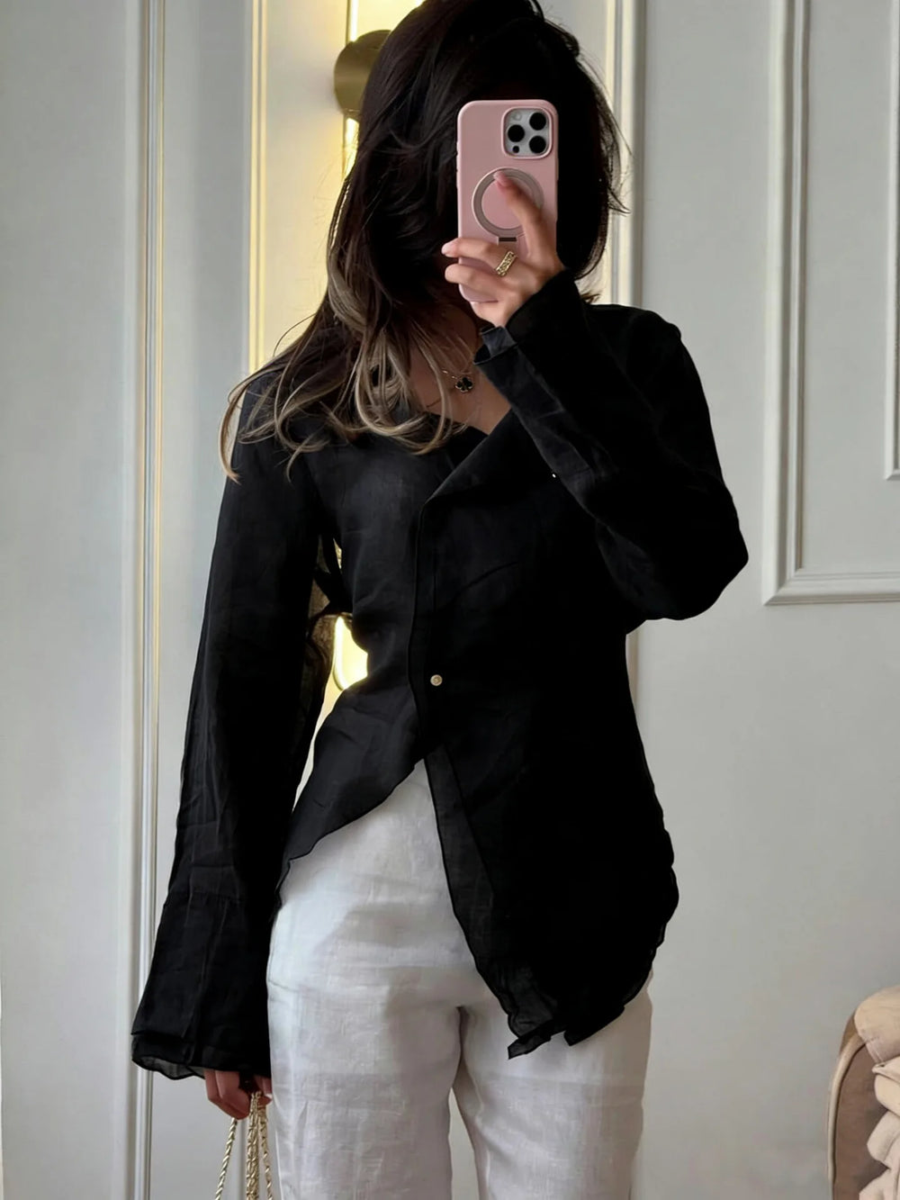 Person wearing a black shirt and white pants in front of a white door.