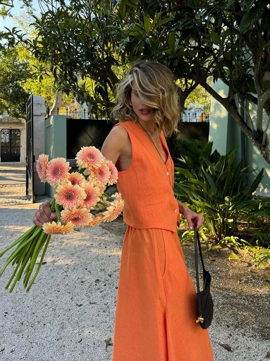 Woman in an orange outfit holding flowers outdoors