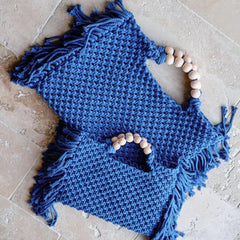 Blue knitted item with tassels and beads on a textured surface